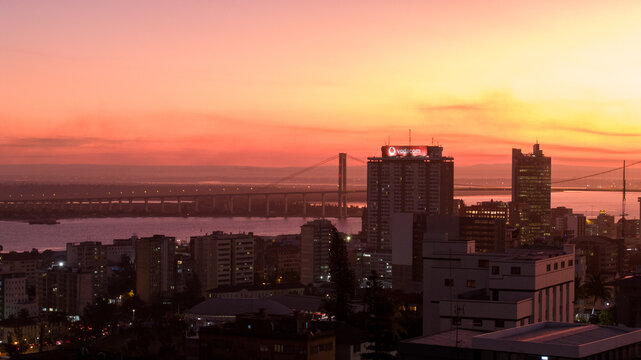 Aerial view of the cityscape bathed in the warm glow of sunset, with the iconic Maputo-Katembe bridge stretching across the bay, Maputo, Cidade de Maputo, Mozambique.