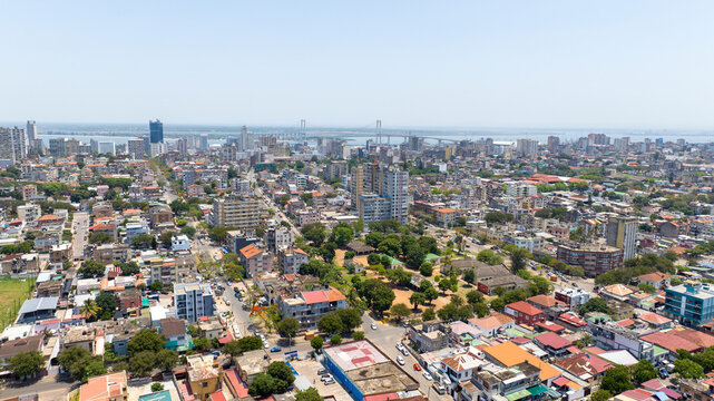 Aerial view of the bustling city streets, vibrant rooftops, and verdant parks contrast against the distant bridge spanning the shimmering bay, Maputo, Cidade de Maputo, Mozambique.