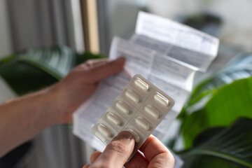 painkiller, hands holding pills package and reading medication instruction information about dosage and side effects