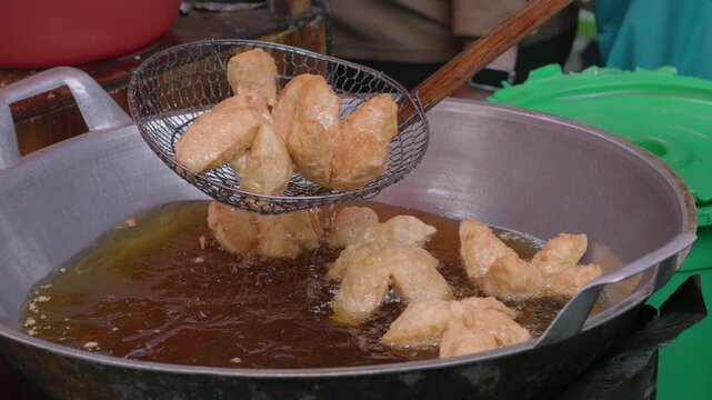 Indonesian street food vendor fries Deep Fried Meatballs or 'Bakso Goreng' in a frying pan with hot oil. 'Bakso Goreng' is Popular Indonesia Street Food