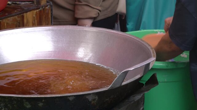Indonesian street food vendor prepares and fries Deep Fried Meatballs or 'Bakso Goreng' in a frying pan with hot oil. 'Bakso Goreng' is Popular Indonesia Street Food