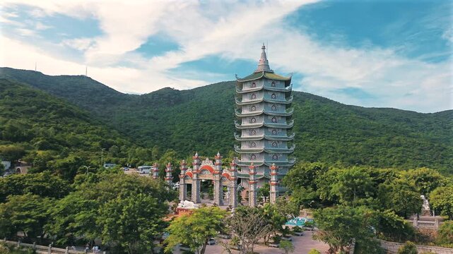 Wide aerial shot showcasing the magnificent multi-tiered Xa Loi Pagoda tower and the ornate entrance gate, set against the lush green mountains of Son Tra Peninsula.
