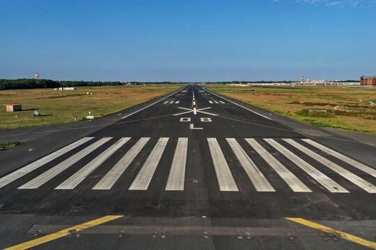 Aerial view of the stark runway lines cutting through the landscape at Flughafen Tegel under a clear sky, Berlin, Berlin, Germany.