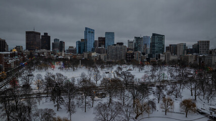 Aerial view of a snow-dusted Boston Common park under a grey sky, with skyscrapers rising in the background, Boston, Massachusetts, United States.