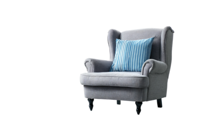 A cozy wingback armchair with a striped blue pillow against a stark black backdrop
