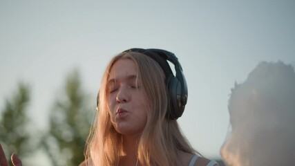 dreamy carnival white teen enjoying headphones gazing at sunset, slow bites of cotton candy, whimsical smile, influencer pose, aspiring singer mood, closeup emotion, soft sunlight, nostalgic evening