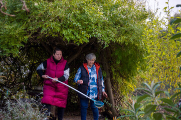 Dwie kobiety wspólnie pracujące przy oczku wodnym w ogródku. © Monika