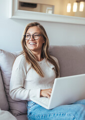 Smiling Woman With Glasses Working On Laptop At Home In Cozy Living Room
