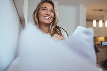 Smiling Woman Laughing on a Couch with Pillow in a Bright Modern Living Room Today