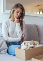 Thoughtful Woman Sits on Couch With Boxed Blanket, Reflecting at Home in Cozy Mood