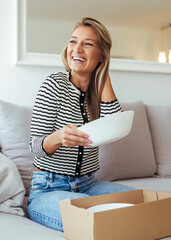 Joyful Woman Unpacking a Plate From a Cardboard Box at Home, Casual Living Room Scene
