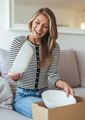 Happy Woman Packing Kitchen Items At Home While Laughing In Striped Top And Jeans