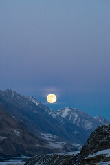 Full moon in the mountains. A beautiful large full moon rose above a mountain peak
