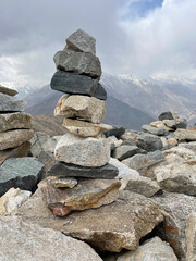 Obraz premium Stacked stones on a mountain peak during cloudy weather near a range of mountains