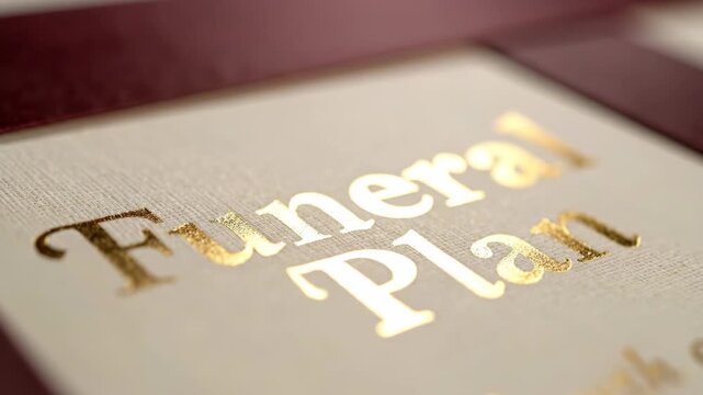 Gold foil 'Funeral Plan' inscription on a document. Close-up with rack focus on important end-of-life arrangements and planning