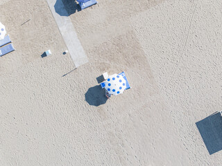 Aerial view of sun-kissed sands dotted with blue and white umbrellas casting shadows on the beach, Forte dei Marmi, Tuscany, Italy.