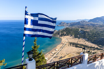 View of Tsambika Beach from above with Greek flag vacation at the Aegean Sea Rhodes island, Greece