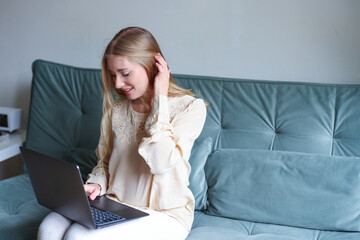 Young female using laptop on sofa at home showing comfortable home office digital work and productivity