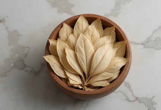 Beautifully arranged dried leaves in a rustic wooden bowl on a elegant marble background. banaba