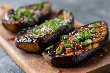 Grilled eggplant with sesame and green onions on board