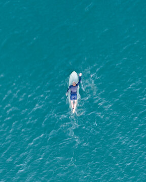 Aerial view of a lone surfer resting on their board amidst the vast, turquoise expanse of the Pacific Ocean, La Saladita, Guerrero, Mexico.