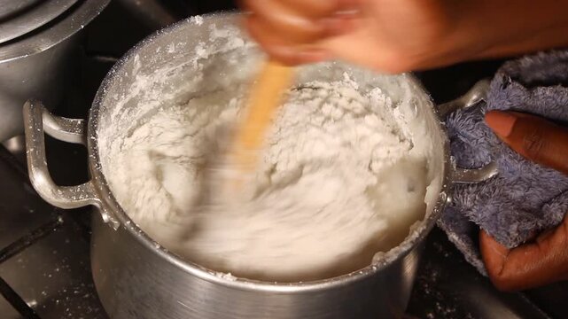 Stirring Maize and Cassava Flour on a Charcoal Stove to Prepare Traditional African Staple Food Known as Ugali, Nshima, Sadza, or Xima