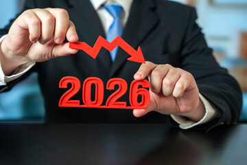 2026 with downward arrow. Declining trend, decrease, drop, financial loss, falling graph, negative growth, business downturn, economic decline, performance drop, market reduction. Man hands