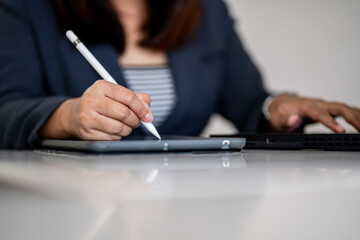 Businesswoman working with tablet and laptop using digital pen, multitasking workflow, modern office technology, creative professional, productivity and smart working concept.