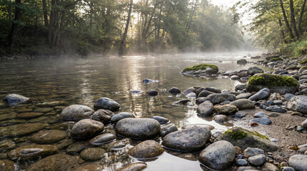 Misty river flowing through a forest at sunrise. Atmospheric morning landscape with smooth stones and sunlight beams. Biblical background concept for the Baptism of Jesus