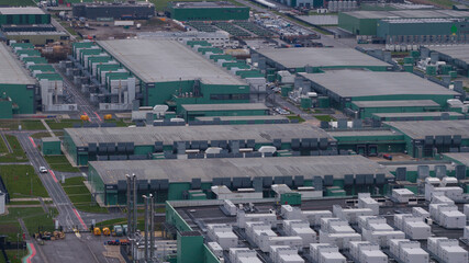 Aerial view of rows of industrial green buildings and containers under a cloudy sky, Agriport, Middenmeer, Netherlands.