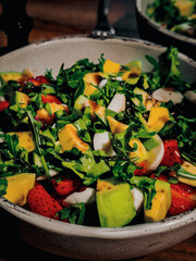 Salad with strawberries, arugula, mozzarella and avocado, teriyaki sauce, top view. High quality photo