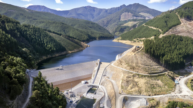 Lee Valley, New Zealand - 24 January 2024: Aerial view of a dam nestled between verdant hills and stark earth, contrasting the engineered structure with the raw beauty of nature.