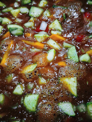 Simple vegetable soup with carrots, celery, zucchini, and tomatoes, vertical view, close-up. High quality photo