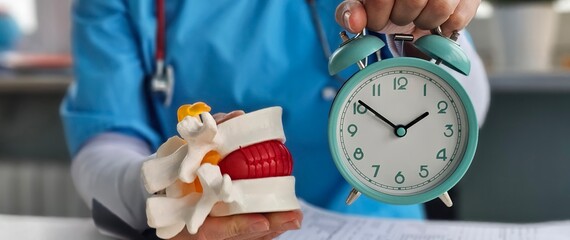 Spine with a hernia alarm clock in the hands of a traumatology. Intervertebral disc herniation and treatment time concept