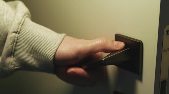 A person uses a doorknob to enter a room.
Metal handle on the door