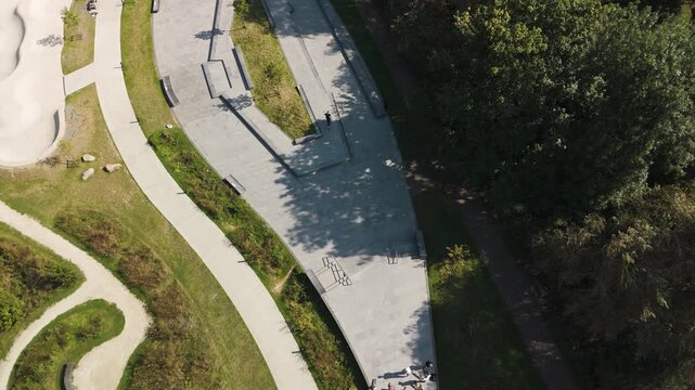 Slow tracking drone shot of young people at a skatepark in England with long shadows at sunset ending with a bail
