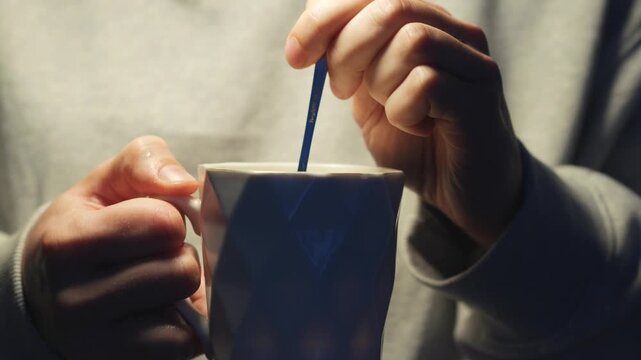 A teacup and spoon in a glass.
Hot tea in a glass.
A man warms himself holding a cup of hot tea in his hands.