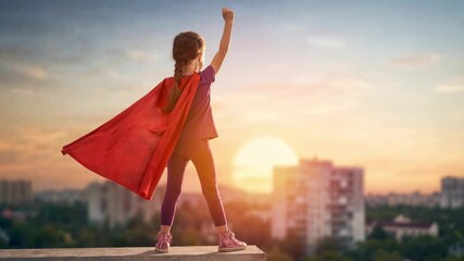Young girl wearing superhero cape standing on rooftop at sunset symbolizing confidence and empowerment for future women.
