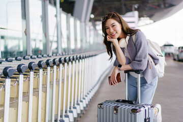 Asian woman traveler with luggage waiting at airport terminal