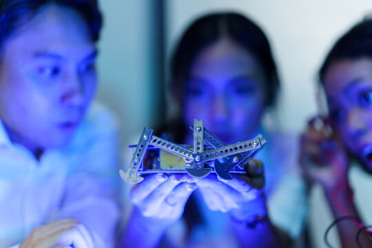 Engineering students testing robotic hand prototype with electronic tools