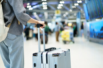 Close up traveler holding suitcase at airport terminal