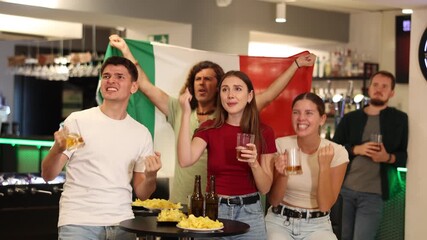 Italian fans with Italian flag emotionally watch the match on TV in a pizzeria. High quality 4k footage