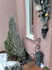 A skeleton doll with a skull and hat hangs on the porch of a house decorated for Christmas