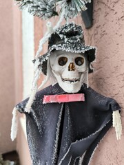 Close-up of a skeleton doll with a skull and hat hanging in winter