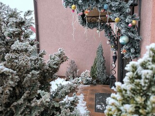 Decorating the porch of a house with Christmas tree decorations, green trees covered with frost