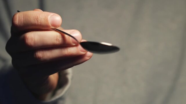 A teaspoon in the hands of the bartender.
Metal tea spoon