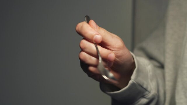 A teaspoon in the hands of the bartender.
Metal tea spoon