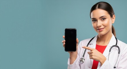 Smiling nurse in blue scrubs with a stethoscope pointing at a blank smartphone screen.