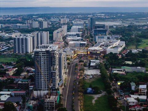 Aerial view of modern buildings casting long shadows as dusk settles over the cityscape near Megaworld Boulevard, Iloilo City, Western Visayas, Philippines.