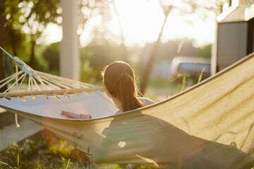 Young woman relaxing in a hammock during sunset, surrounded by nature, evoking tranquility and peace, perfect for wellness and relaxation themes